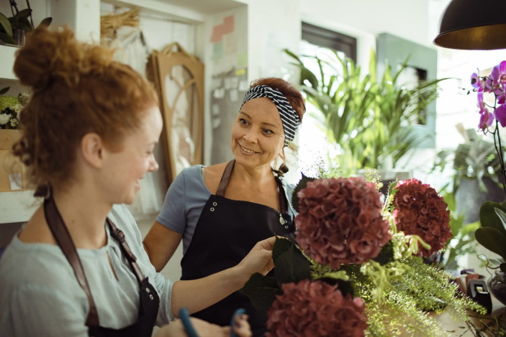 To butikkansatte i en blomsterbutikk som prater sammen